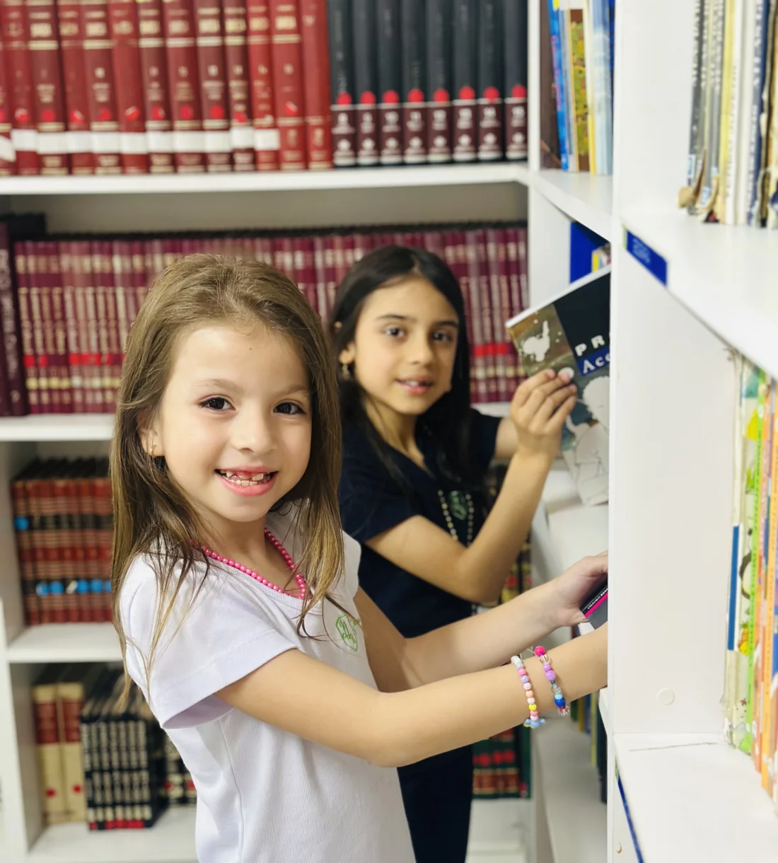 Duas alunas do Colégio JJR escolhendo livros na biblioteca